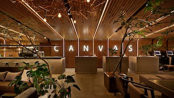 A modern interior with wooden paneling, a reception desk, seating areas, and potted plants.