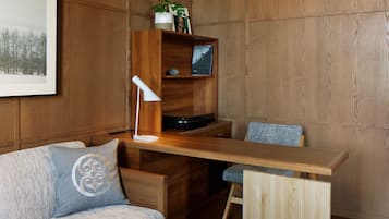 Een houten kamer met een lange tafel, een bank en een boekenkast.
