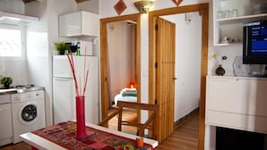 Una cocina funcional con lavadora, una mesa de comedor con camino de mesa y una silla de madera.