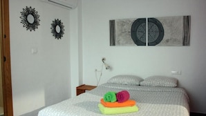 Un dormitorio con una cama, dos adornos de pared, un reloj de pared y una lámpara de noche.