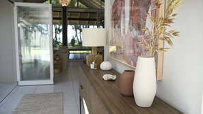 A modern interior with a wooden console table, a white vase with dried plants, and a framed artwork on the wall.