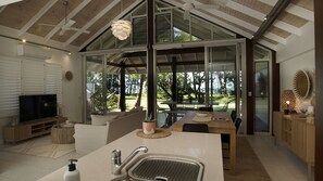 A modern kitchen with a large island, a dining area with a view, and a living room with a television.