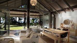 A modern interior with a dining area, sofa, and large windows overlooking a garden.