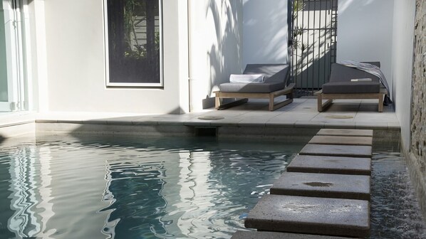 A swimming pool with steps leading into it, surrounded by a white wall and a wooden deck. - Nikatara - Mission Beach (Mission Beach)