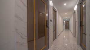 A hallway with doors marked with numbers, a speckled floor, and a modern design. - Gwangan Stay Hotel (Busan)