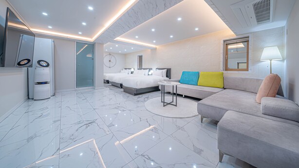 A modern hotel room with a large bed, a sofa, a small table, and a mirror. - Gwangan Stay Hotel (Busan)