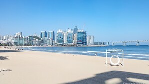 A beach with a city skyline in the background, including a bridge. - Gwangan Stay Hotel (Busan)