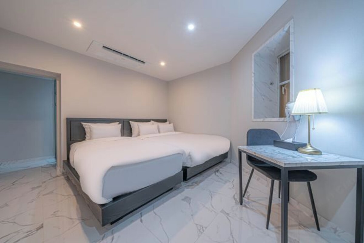 Une chambre à coucher moderne avec un lit, une table de chevet, une lampe et une fenêtre.