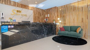 A hotel reception area with a marble counter, a green sofa, and a wooden wall design. - Gwangan Stay Hotel (Busan)