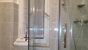 A glass-enclosed shower area with a handheld showerhead and a wall-mounted faucet. - Hotel Genziana (Genoa)