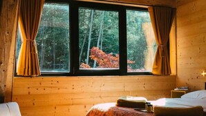 Une chambre confortable avec un grand lit, un fauteuil et une fenêtre avec des rideaux.