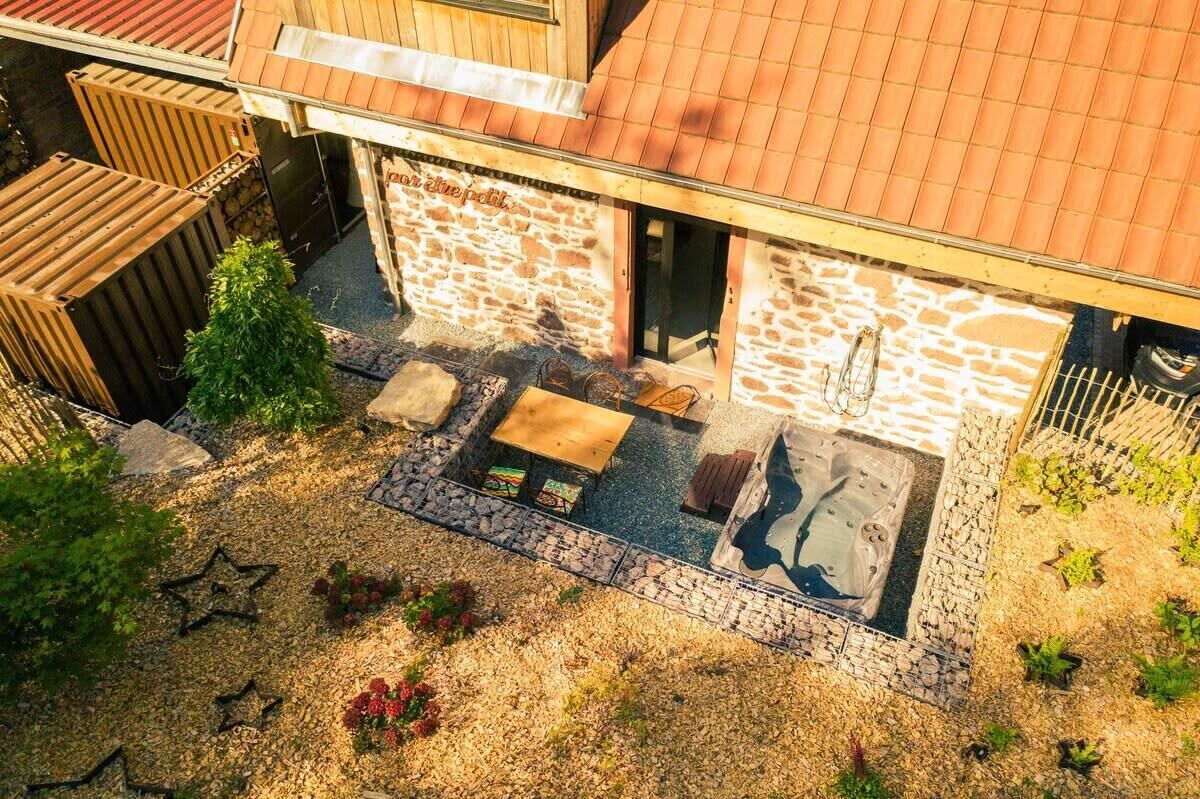 A stone building with a tiled roof, outdoor seating area with a table and chairs, and a small garden with star-shaped decorations.