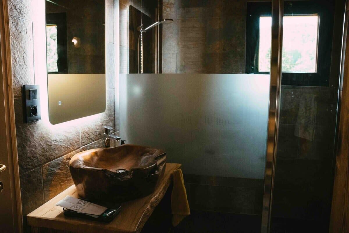 Een badkamer met een ruime, rustieke houten wastafel, een moderne douche en een matglazen wand.