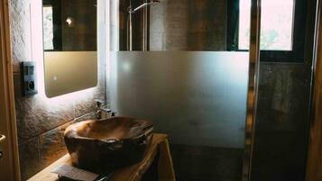 Een badkamer met een ruime, rustieke houten wastafel, een moderne douche en een matglazen wand.