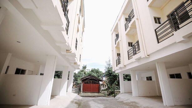 A multi-story building with a central courtyard, featuring balconies and a red gate. - OYO 789 Abn Residences (Bacolod)