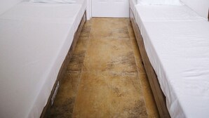 A small, clean room with two single beds, a white door, and a tiled floor. - OYO 789 Abn Residences (Bacolod)