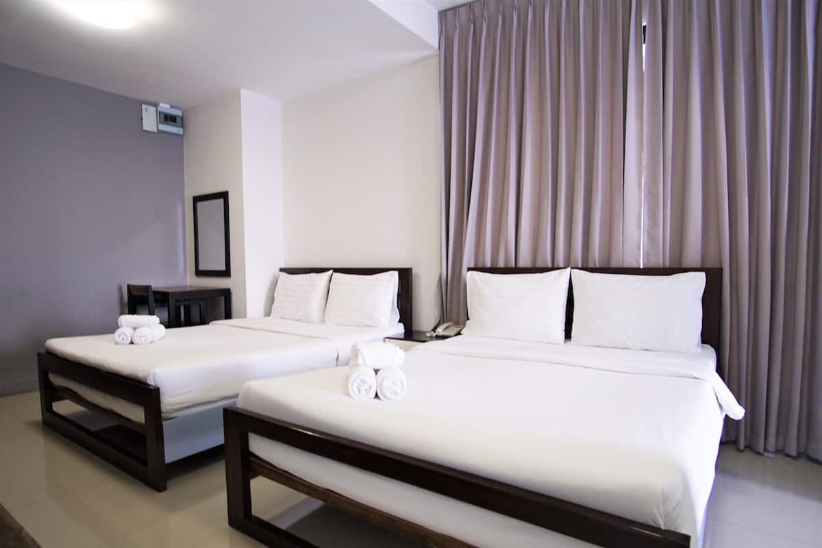 Two twin beds with white linens, a bedside table with a phone, and a window with curtains.