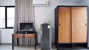 A room with a TV on a wooden table, a refrigerator, and a wardrobe. - Subkamon Apartment (Chiang Mai)