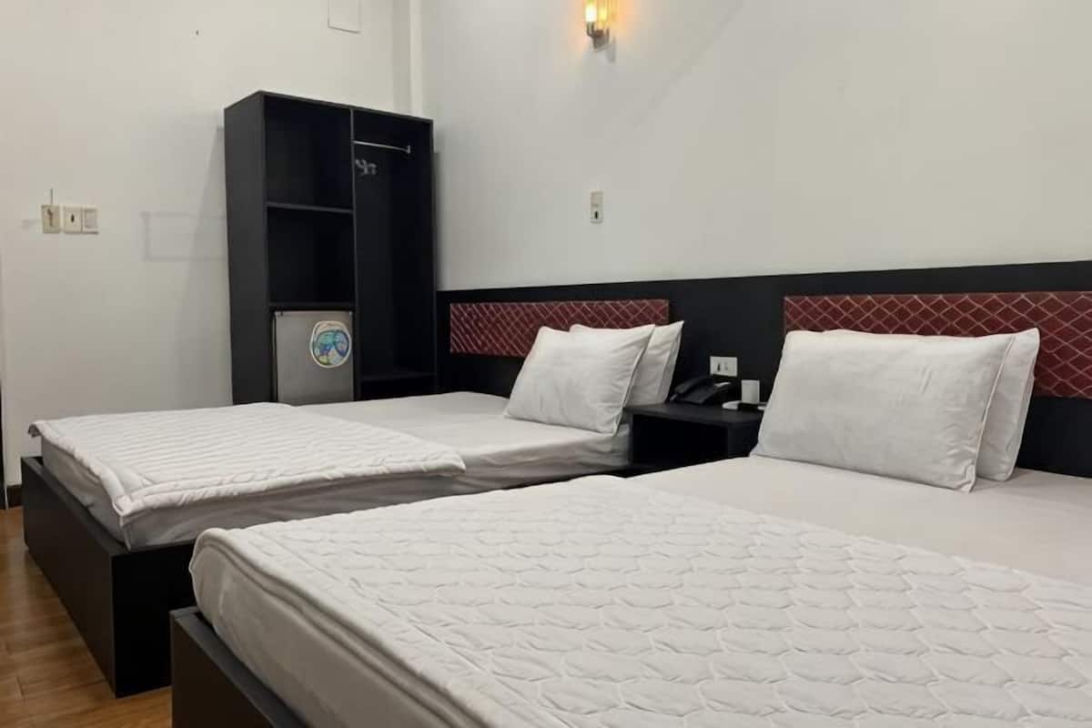 Two single beds with white bedding, a black wardrobe, and a red and white headboard.