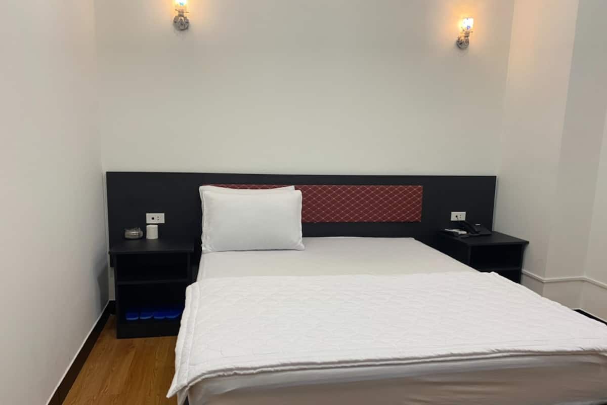 A modern hotel room with a large bed, two bedside tables, and wall-mounted lighting.