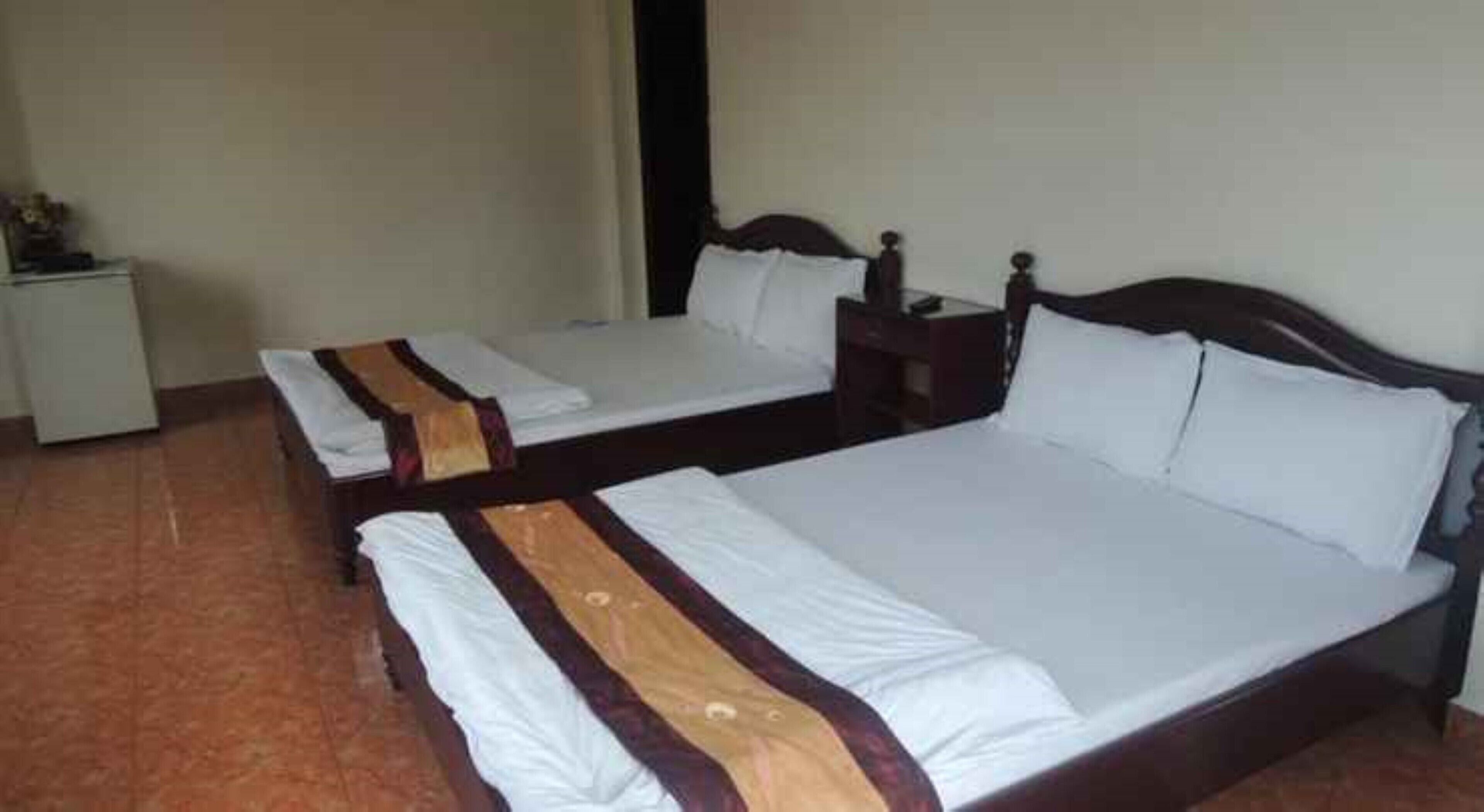 A hotel room with two single beds, each with a wooden headboard and white bedding.