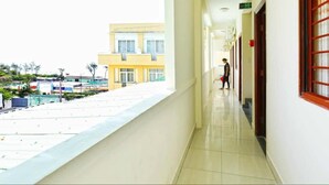 A corridor with a tiled floor and a balcony overlooking a building complex.