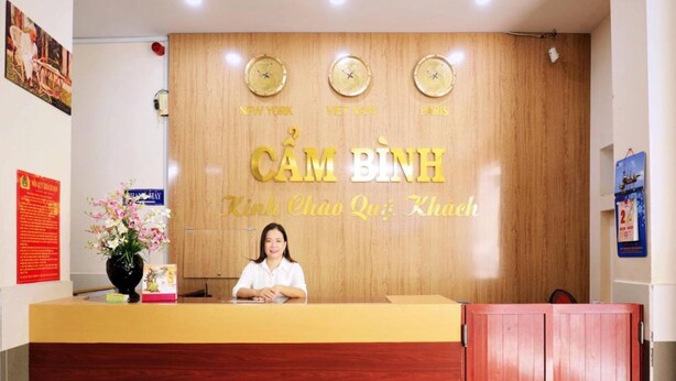 A reception desk with a wooden backdrop and clocks indicating New York, Vietnam, and Paris.