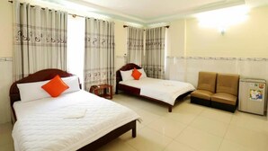 A hotel room with two beds, a sofa, and a refrigerator.