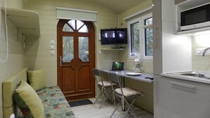 Une cuisine de taille réduite, dotée d’une porte en bois, d’un téléviseur et d’un coin repas avec une table et des chaises.