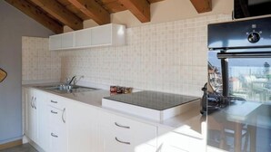 Eine Küche mit weißen Schränken, einer Edelstahl-Spüle und einem schwarzen Kühlschrank.