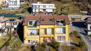 A multi-story residential building with balconies, solar panels, and a garden area.