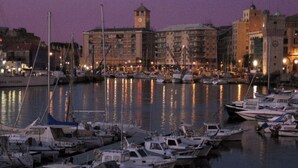 A marina with boats docked at night, surrounded by buildings with a clock tower.