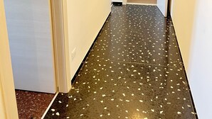 A hallway with a dark floor and white walls, leading to a room with a door.