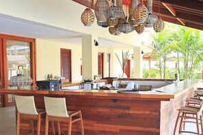 A spacious kitchen with a wooden island, bar stools, and hanging decorative lights. - Jatiuca Hotel and Resort (Maceió)