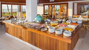 A buffet setup with various food items and a wooden counter. - Jatiuca Hotel and Resort (Maceió)