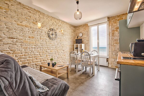 A cozy living room with a stone wall, a wooden table, and a sofa.
