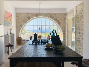 Una cocina con un amplio ventanal de arco, una mesa de comedor y vista al mar.