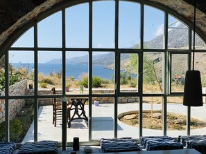 Una habitación con un amplio ventanal arqueado que ofrece una vista panorámica del mar y las montañas.