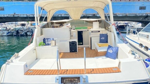 A boat with a covered deck, a central seating area, and a small kitchen. - Boating Oliday (Castellammare di Stabia)