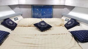A bed with a quilted headboard, two pillows with star patterns, and a view of the sky through a window. - Boating Oliday (Castellammare di Stabia)