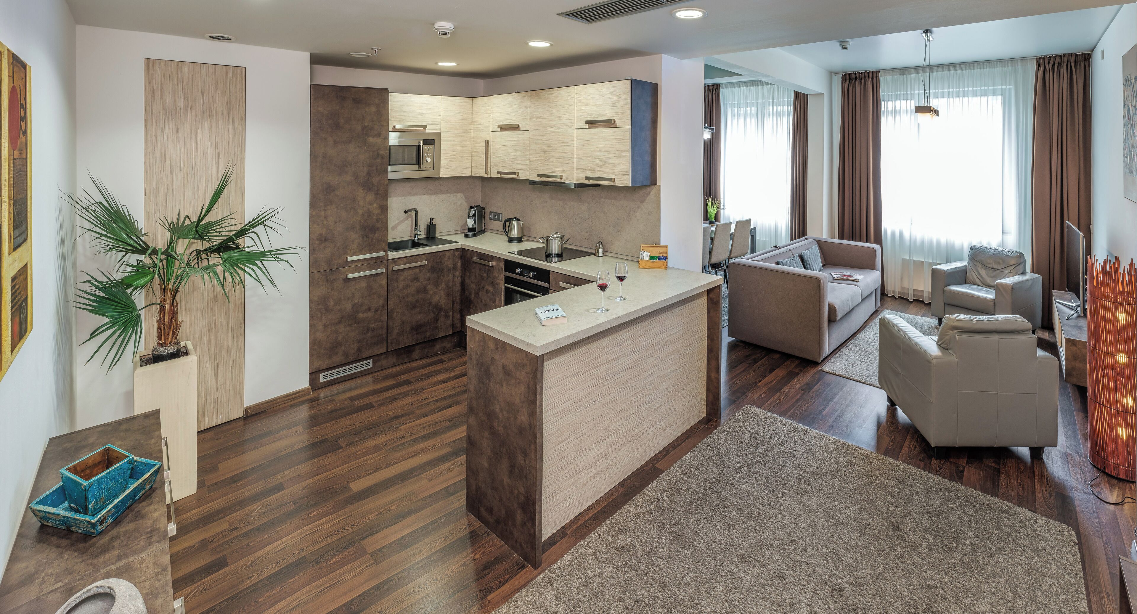 Een moderne keuken met een centraal eiland, een zithoek met een bank en een woonkamer met een televisie.