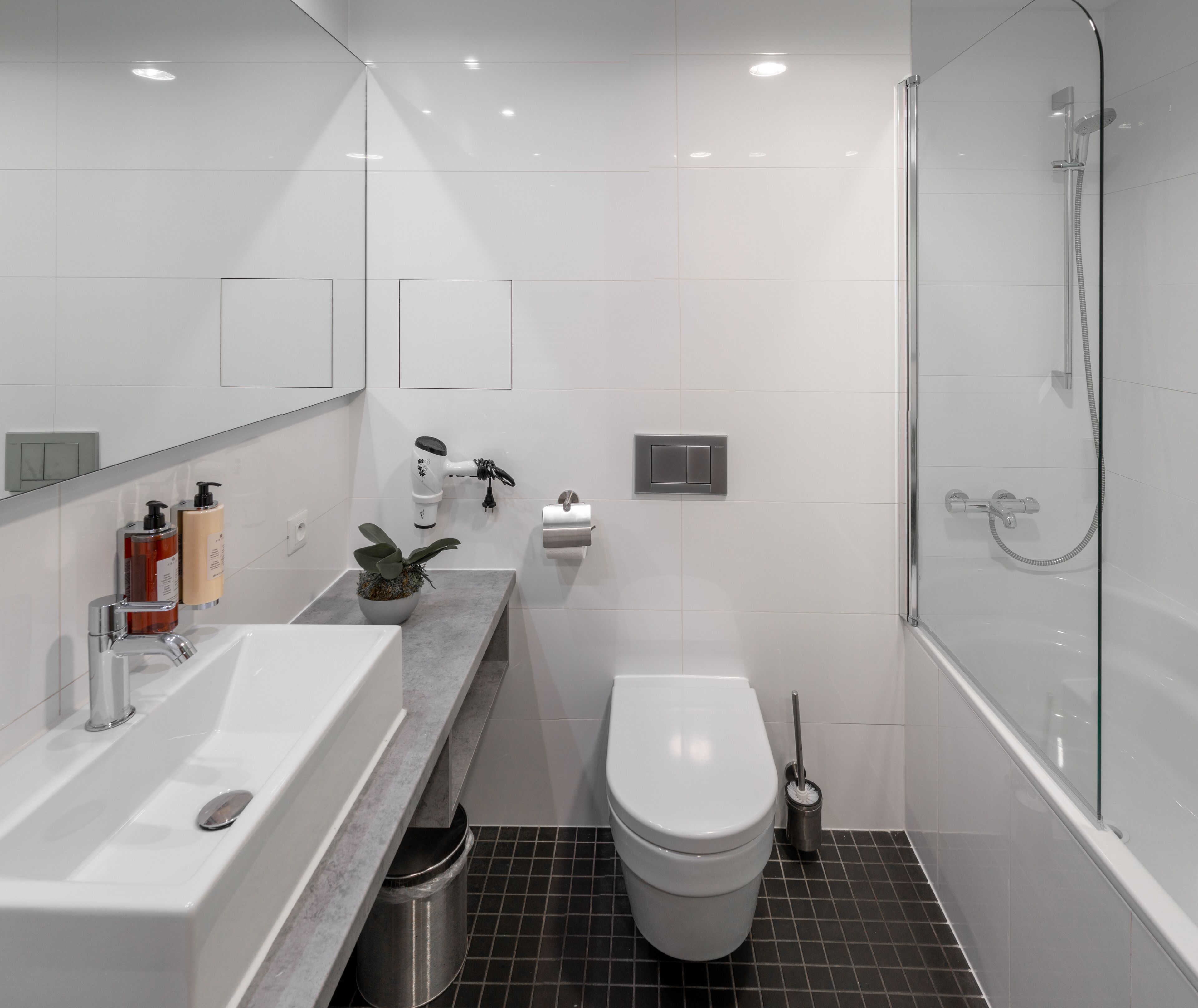Ein modernes Badezimmer mit Waschbecken, Toilette und Dusche, alles in Weiß.