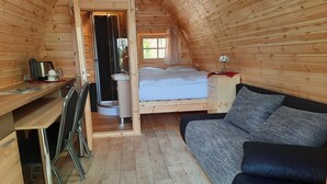 Ein gemütliches Holzhaus mit Schlafkoje, kleinem Schreibtisch und einer Couch.