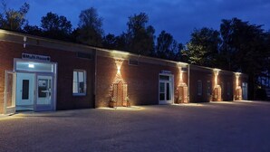 Ein Mehrfamilienhaus mit Backsteinfassade, mehreren Hauseingängen und Außenbeleuchtung.
