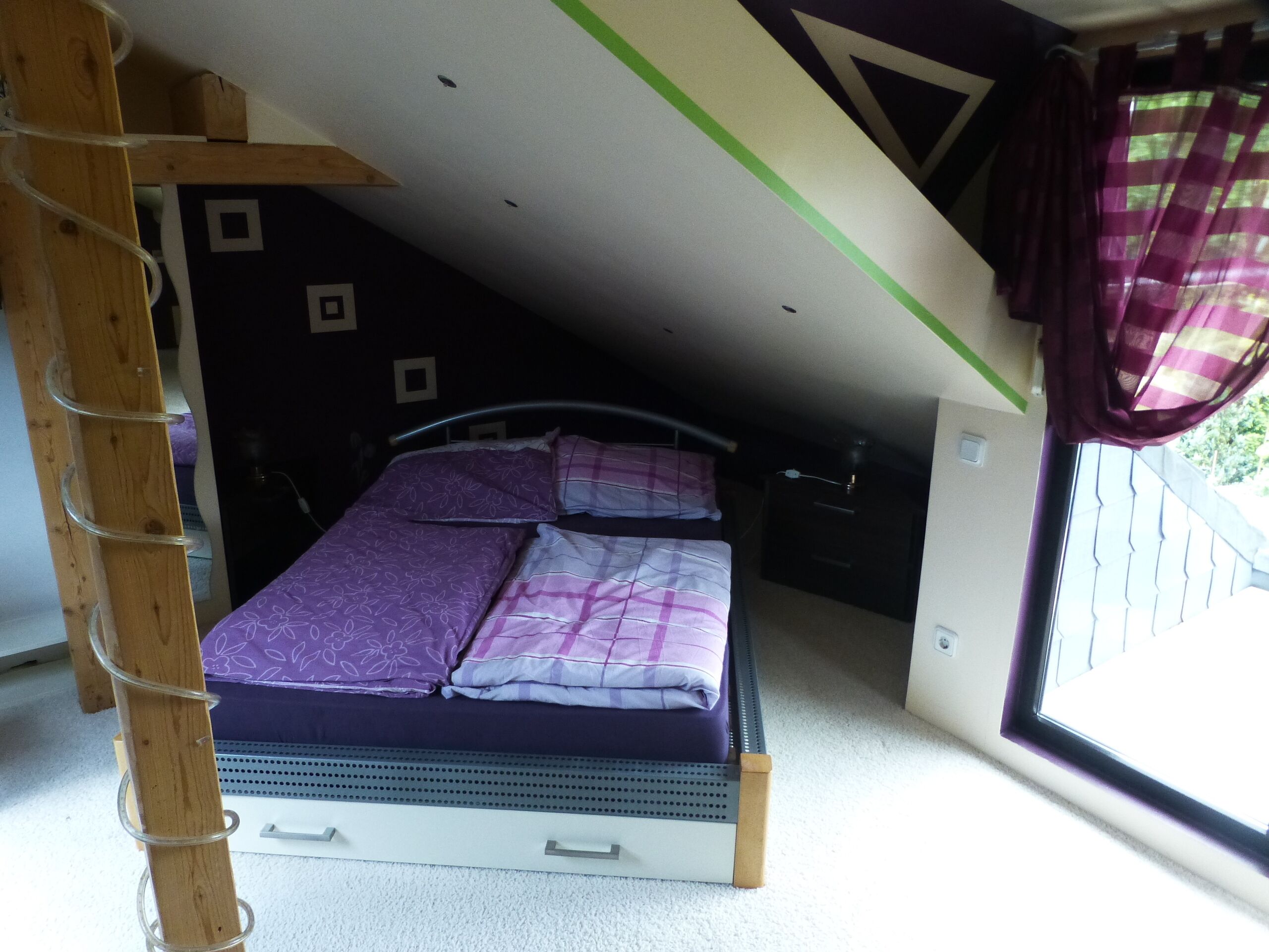 A compact room with a bed, a small desk, and a window with curtains.