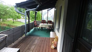 A covered outdoor area with a wooden deck, a table with chairs, and a teddy bear. - Castle view apartment 1 (Großlohra)