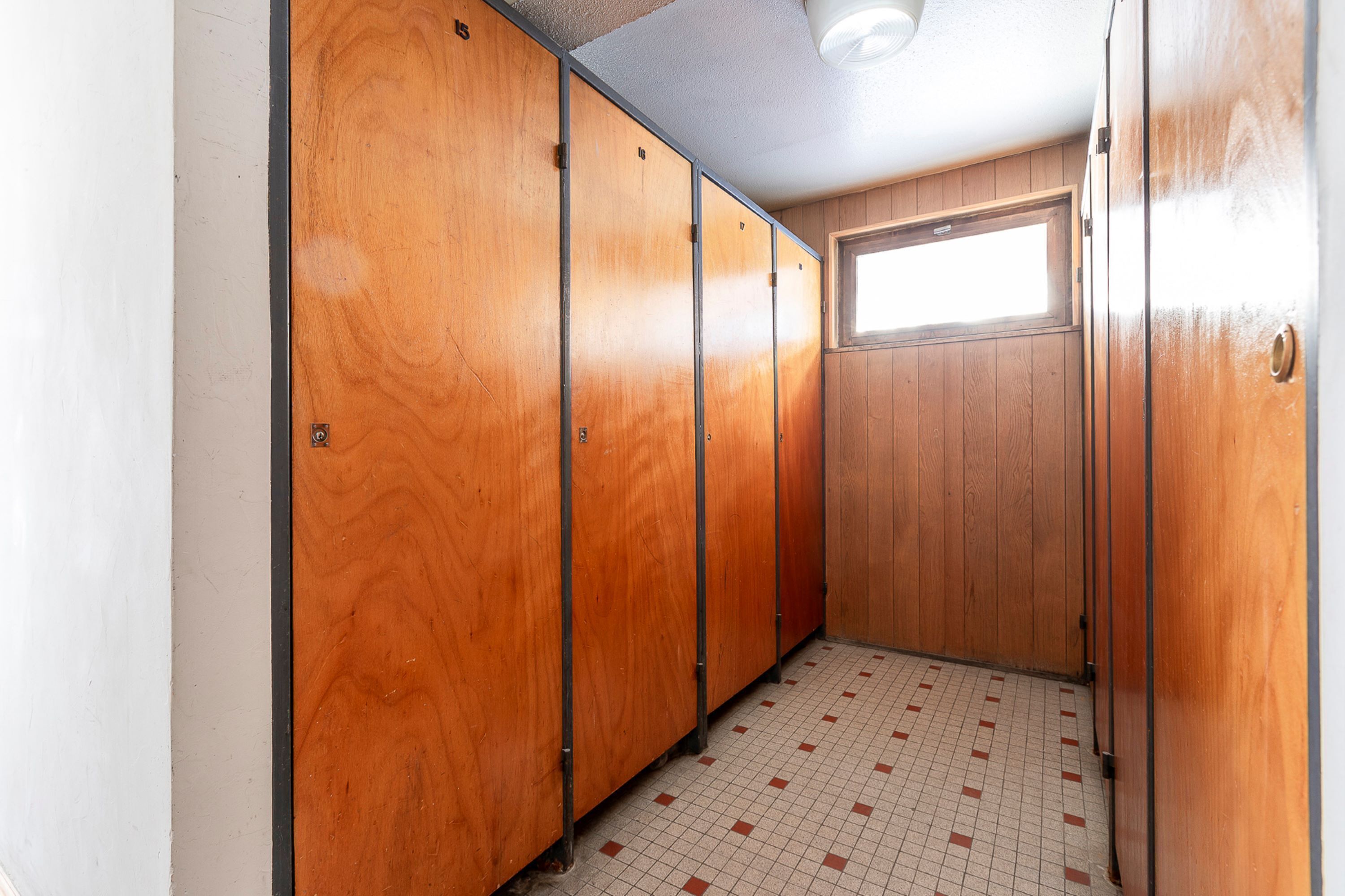A narrow hallway with wooden lockers and a tiled floor.