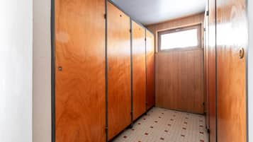 A narrow hallway with wooden lockers and a tiled floor.