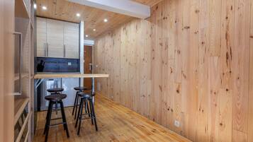 Una cocina compacta con paredes de madera, una barra integrada y tres taburetes.