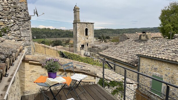 A balcony with a wooden deck, a chair, a table with an open book, and a potted plant. - Paradis de Provence / Leben wie Gott in Frankreich (Verfeuil)